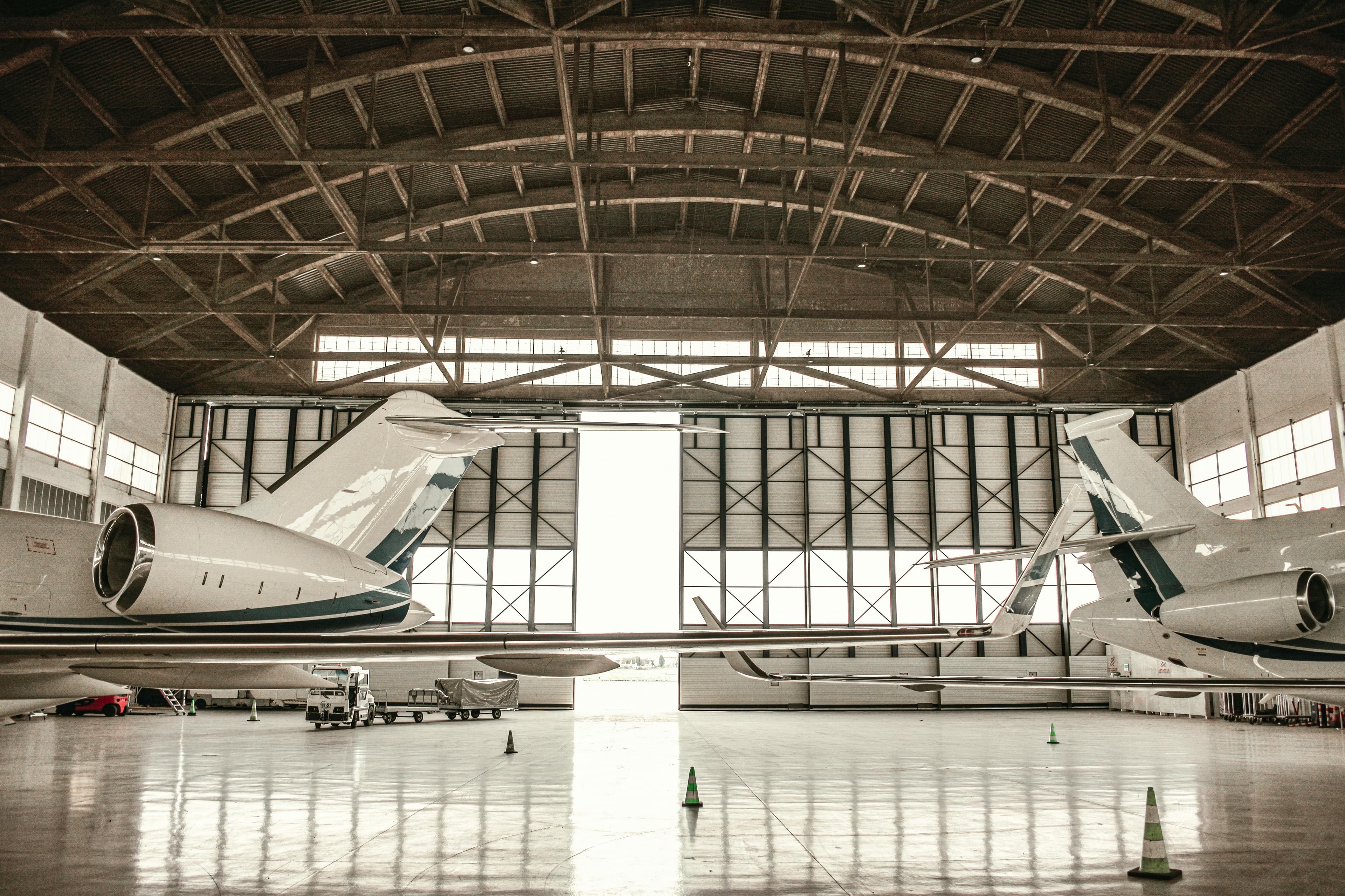 A printed charter quote on a desk next to a midsize jet visible through a hangar window at dusk