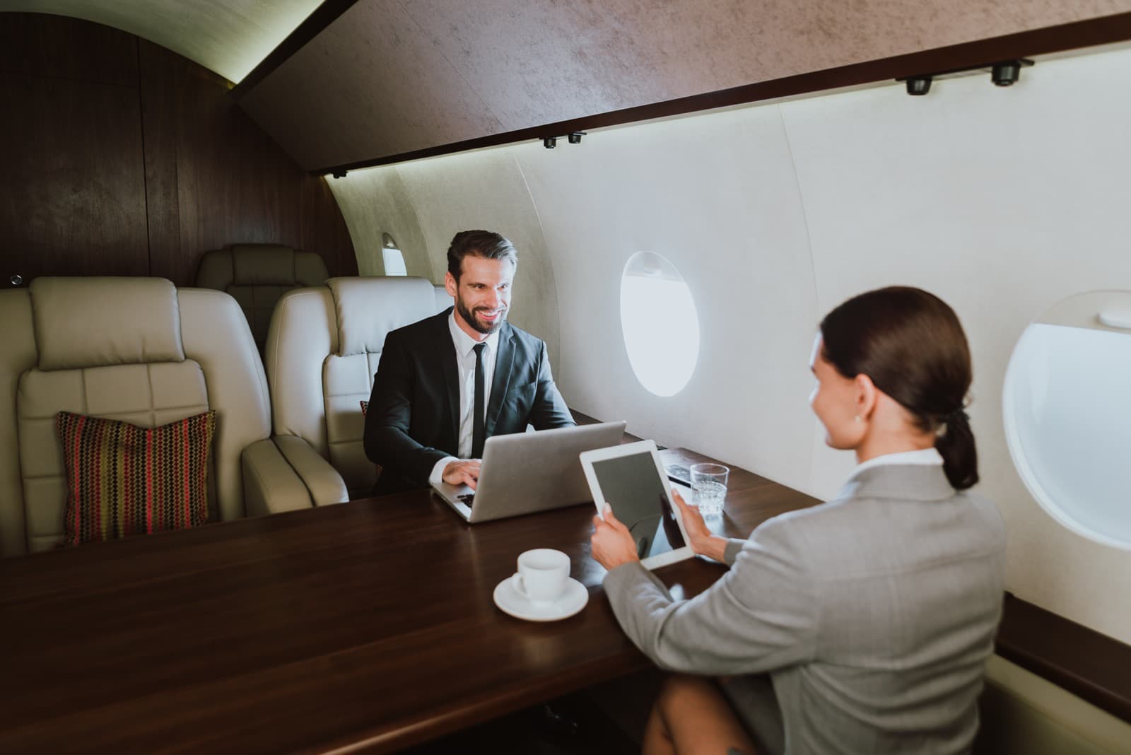 A large-cabin business jet parked on a quiet ramp at dusk with airstairs deployed and cabin lights on