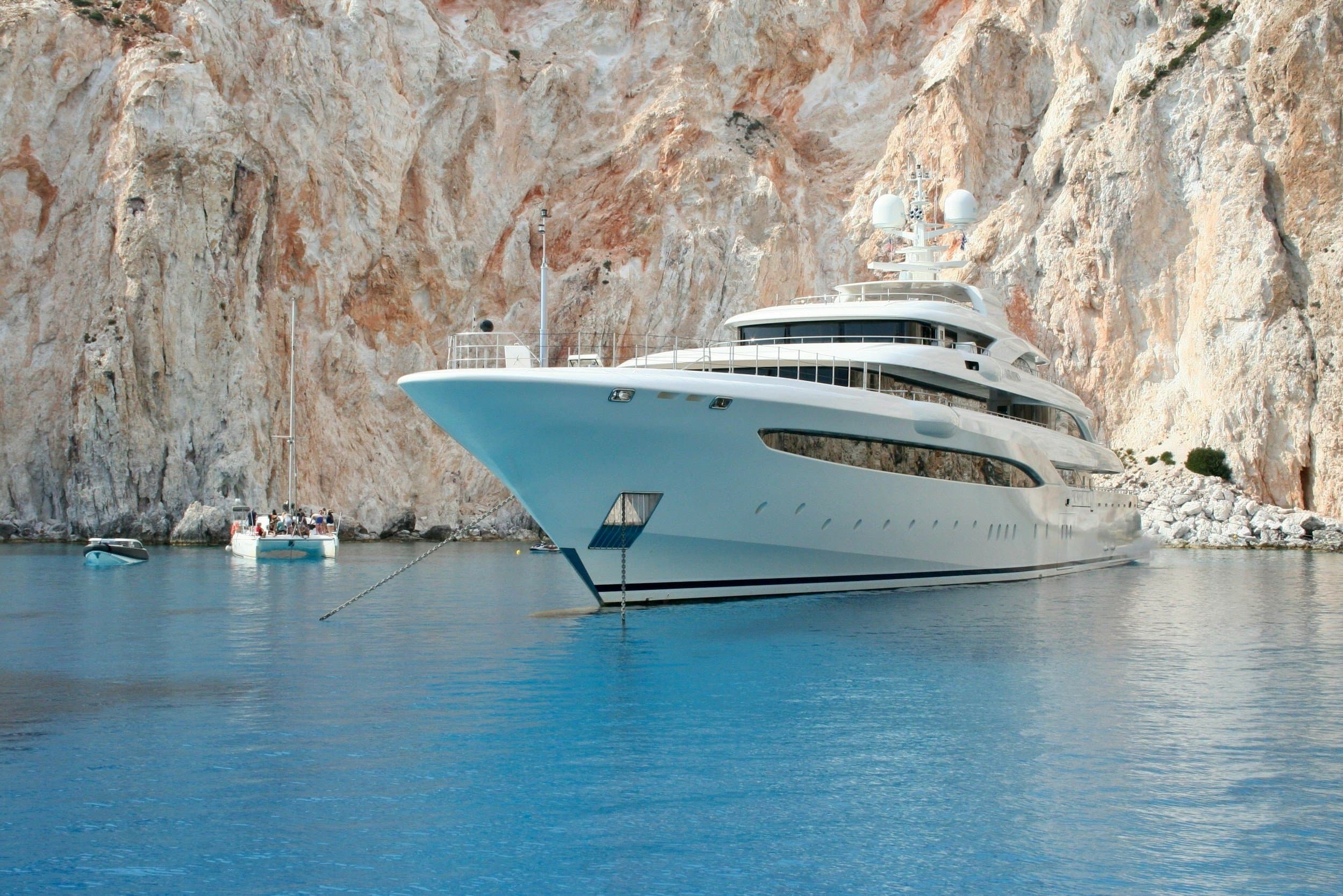 A large motor yacht berthed along Quai des États-Unis in Port Hercule with the Monaco Grand Prix circuit barriers visible on the quayside